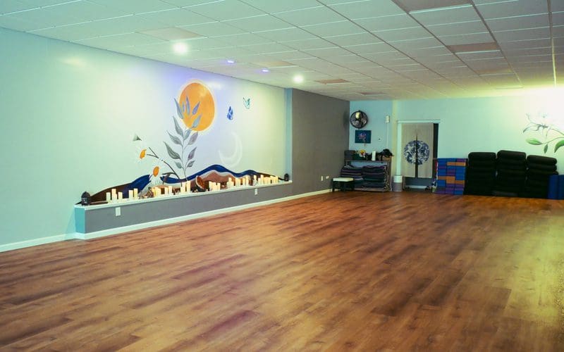 Empty yoga studio with mural and stacked mats