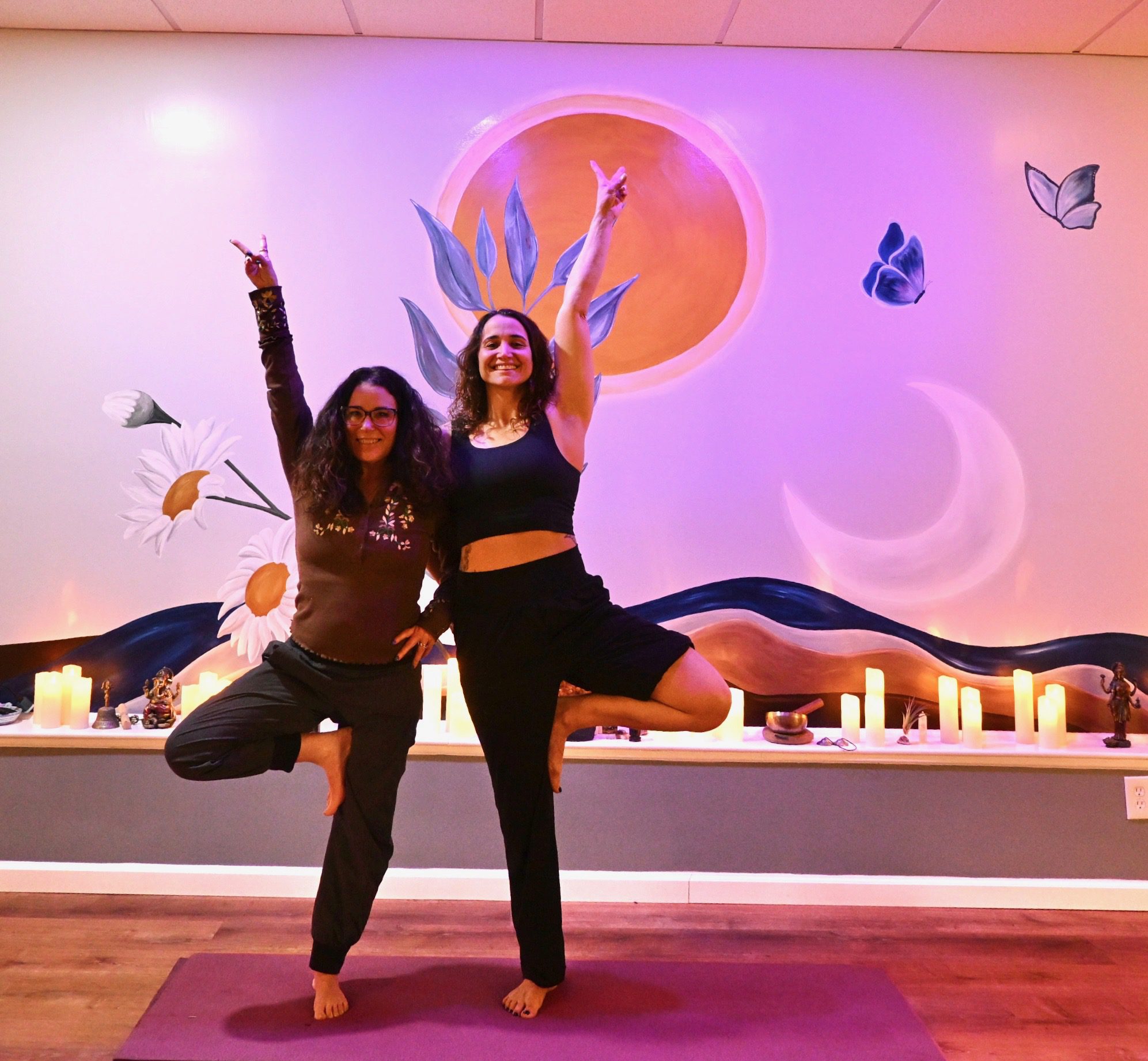 Two women practicing tree pose in studio